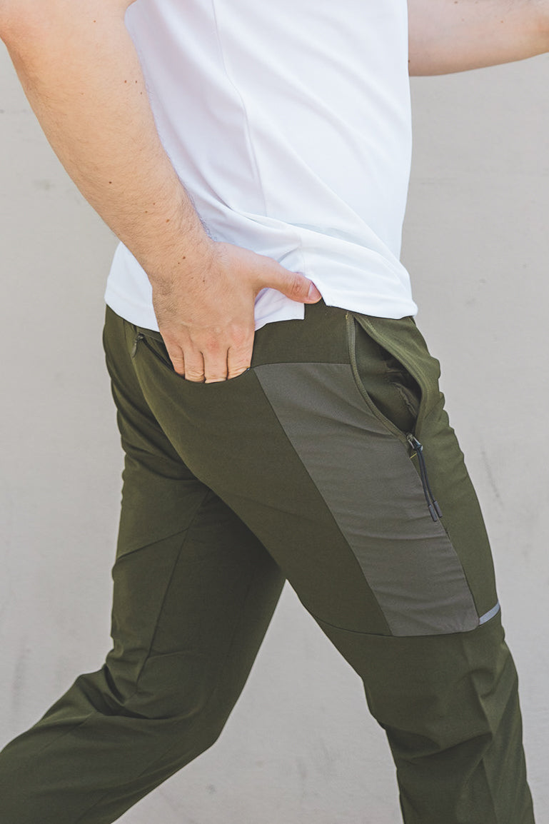 male walking wearing a white t shirt and olive green athletic joggers from under510.com with hand in back pocket