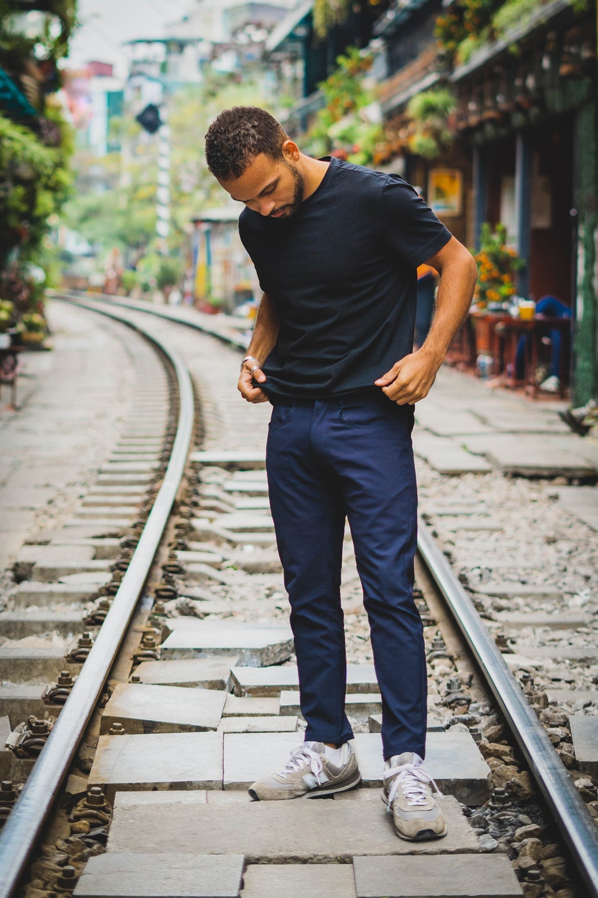 Male model standing on train tracks wearing a navy t shirt with navy super stretch performance pants and new balance sneakers