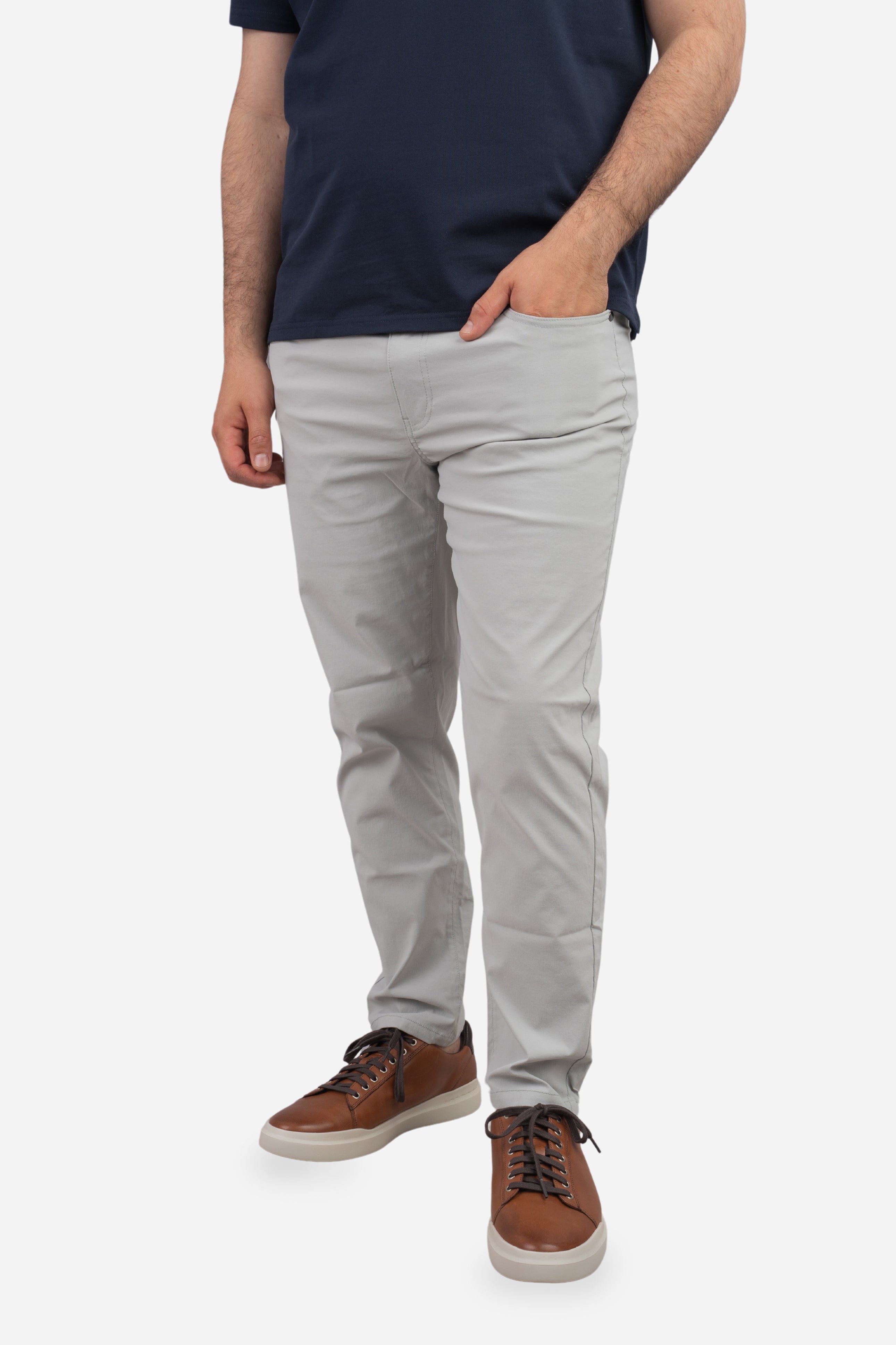 Person wearing light gray pants and brown shoes on a white background