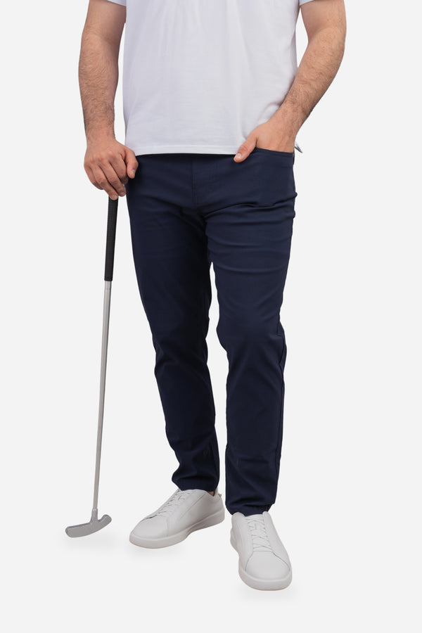 Person wearing navy pants and white shoes holding a golf club on a white background