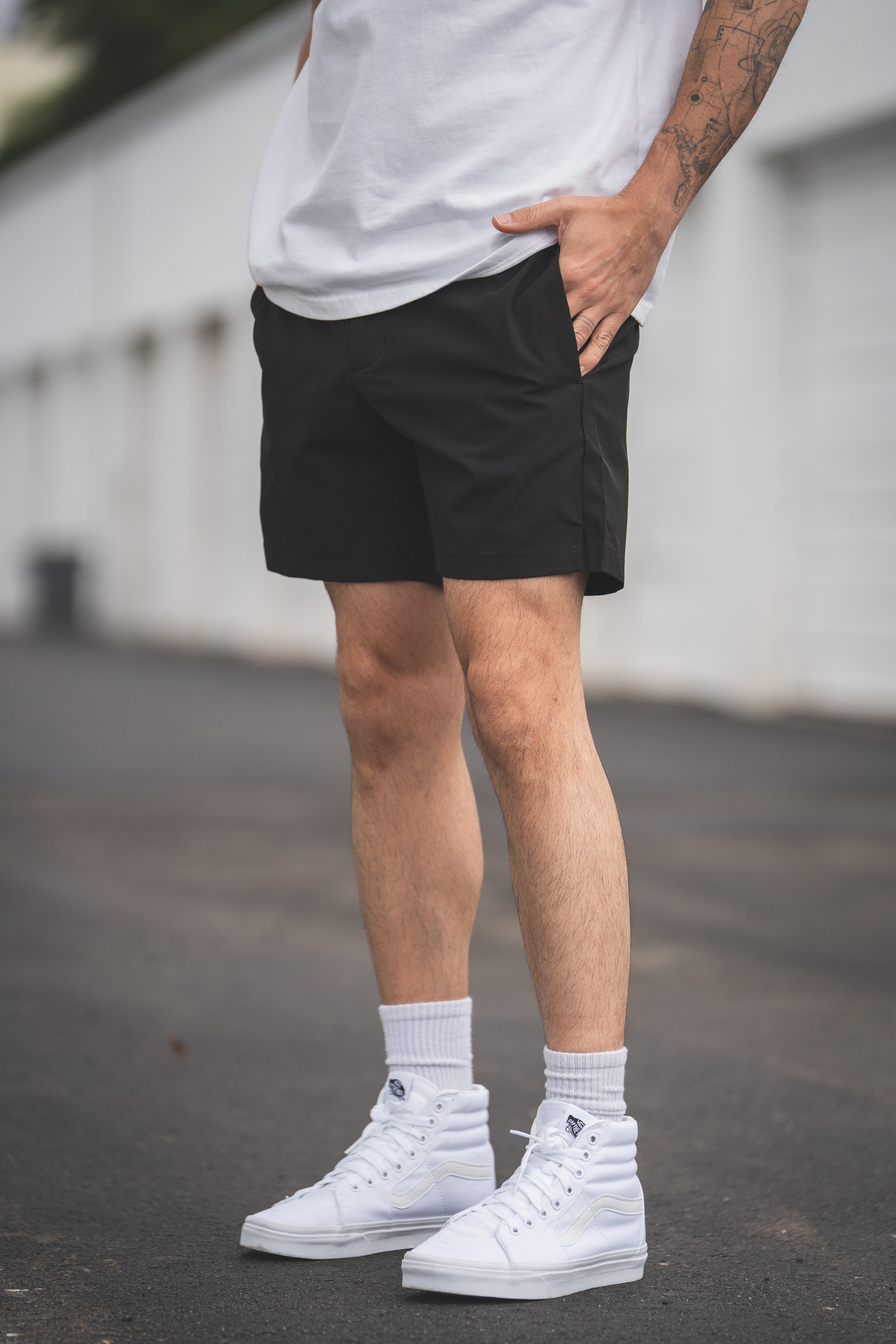 Person wearing black shorts, white sneakers, and socks on a blurred background