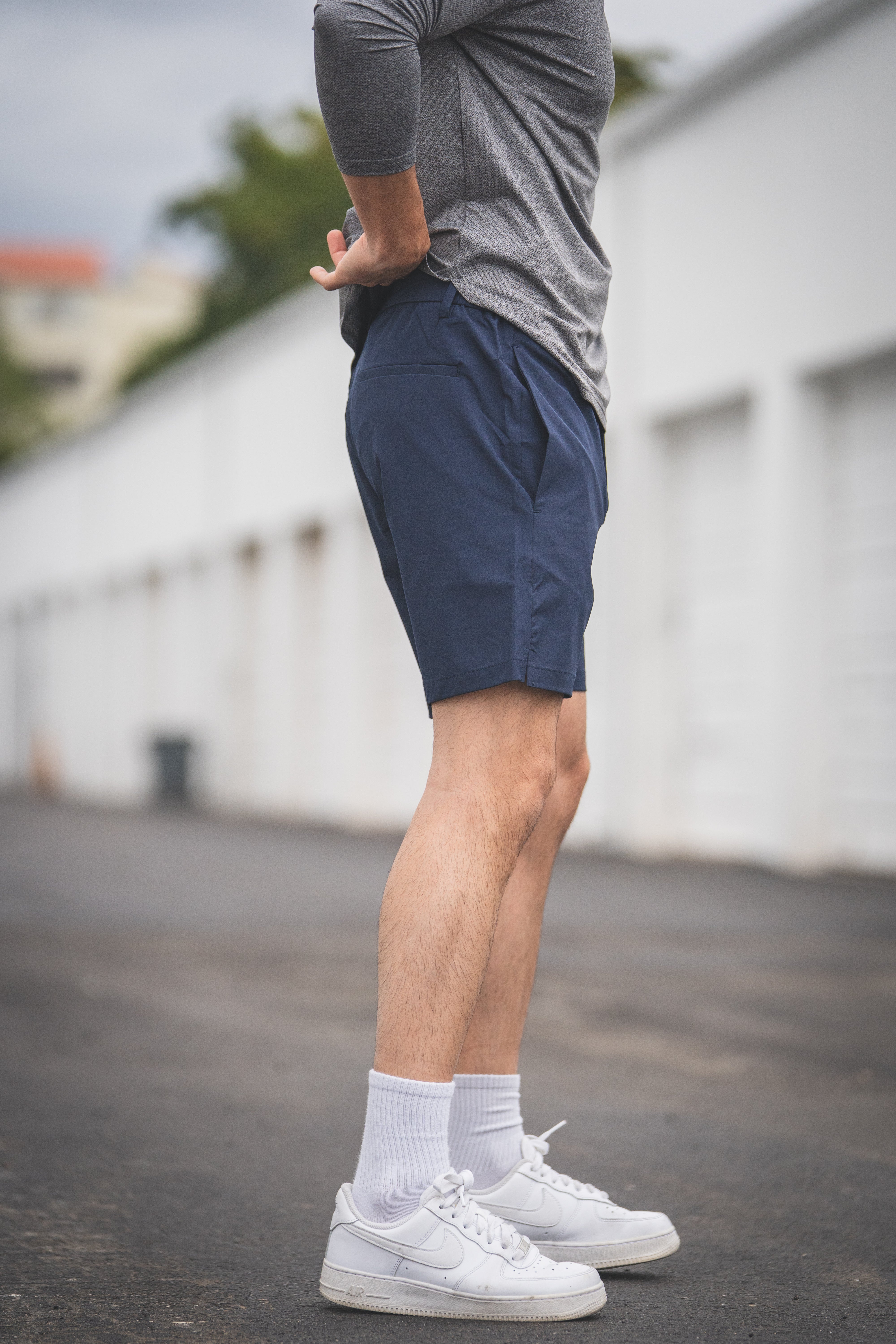 Person wearing navy shorts and white sneakers on a blurred background