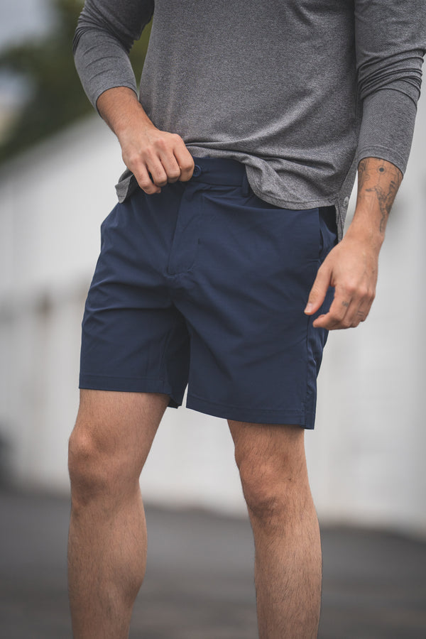 Person wearing navy shorts and a gray long-sleeve shirt outdoors
