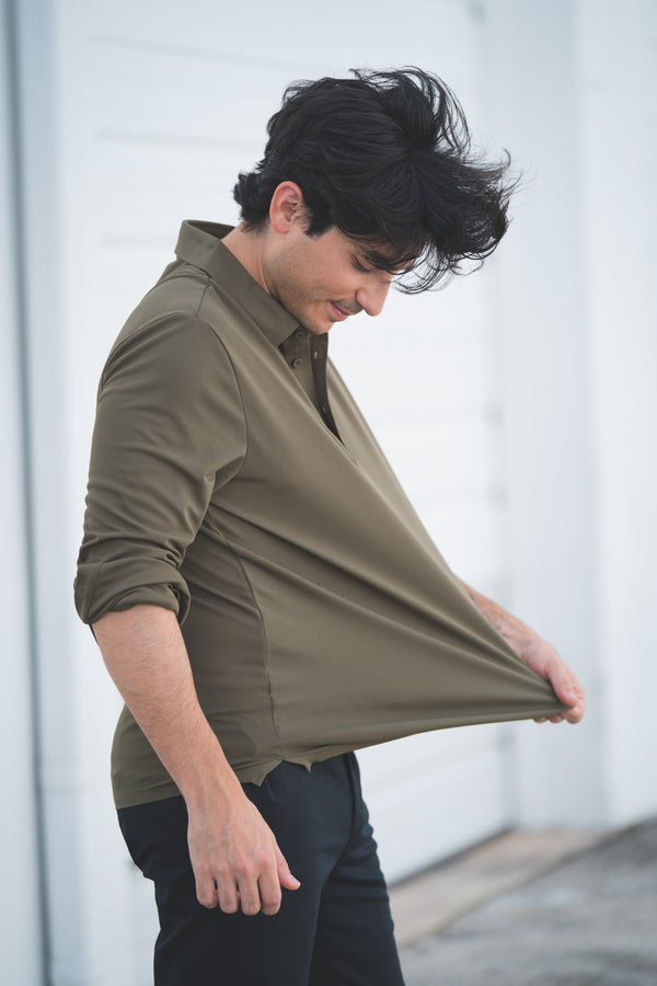 Person wearing a green shirt with rolled-up sleeves, standing against a blurred background.