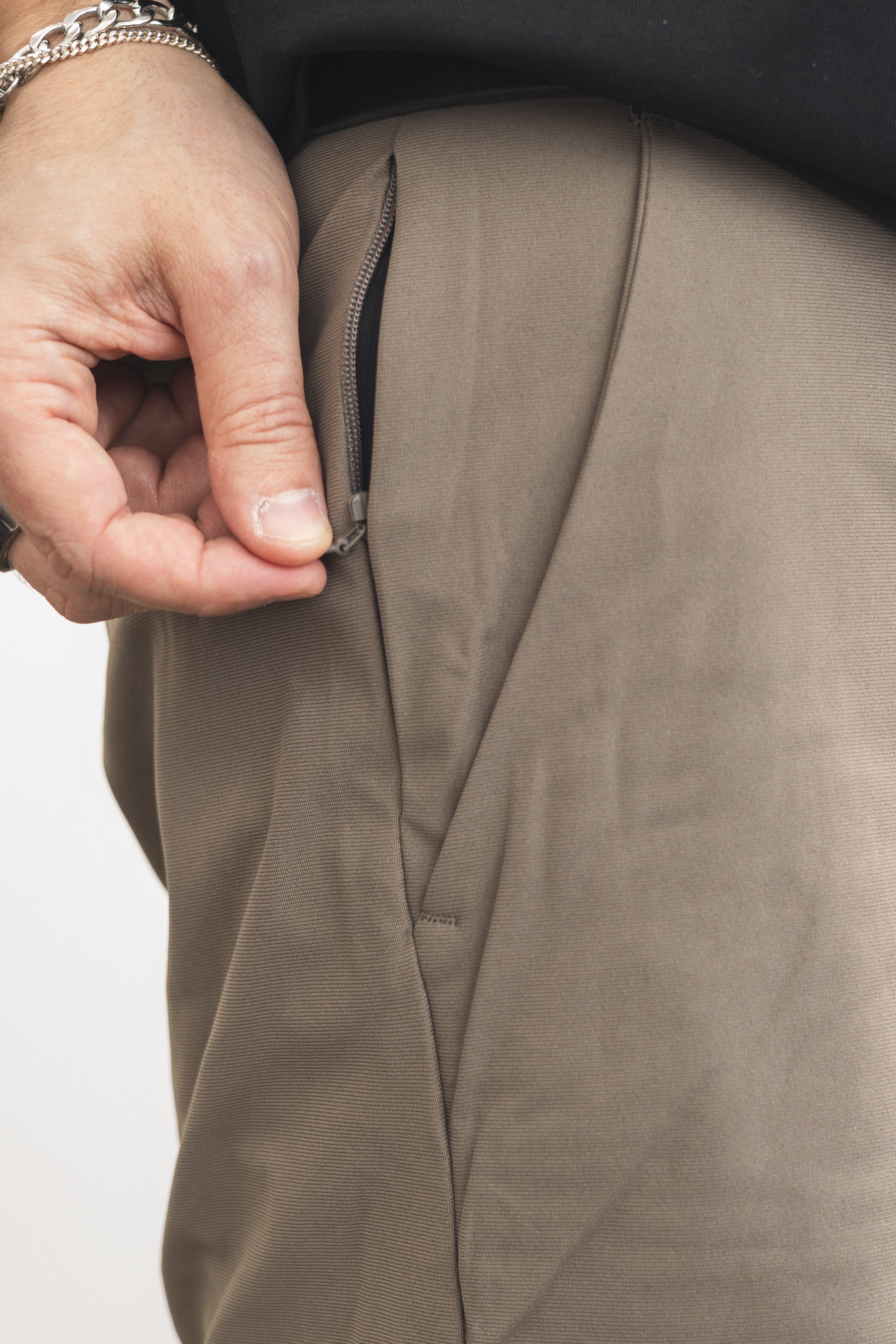 Close-up of a hand zipping up a brown jacket on a white background