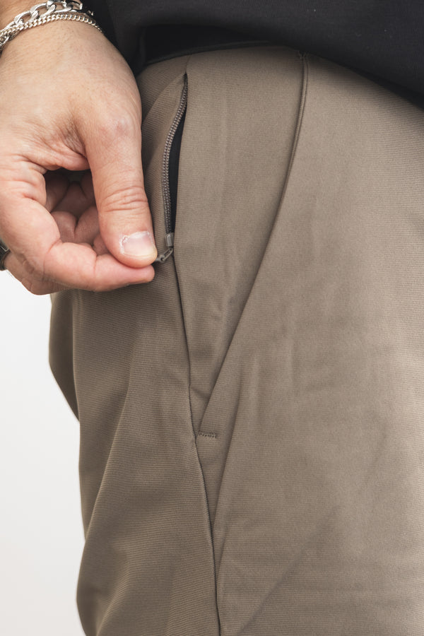 Close-up of a hand zipping up a brown jacket on a white background