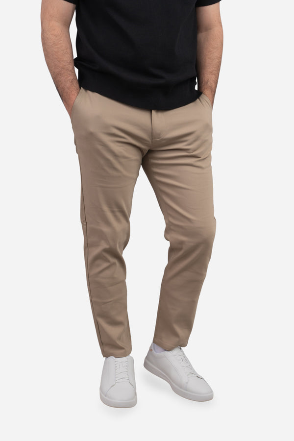 Person wearing beige pants and a black shirt on a white background