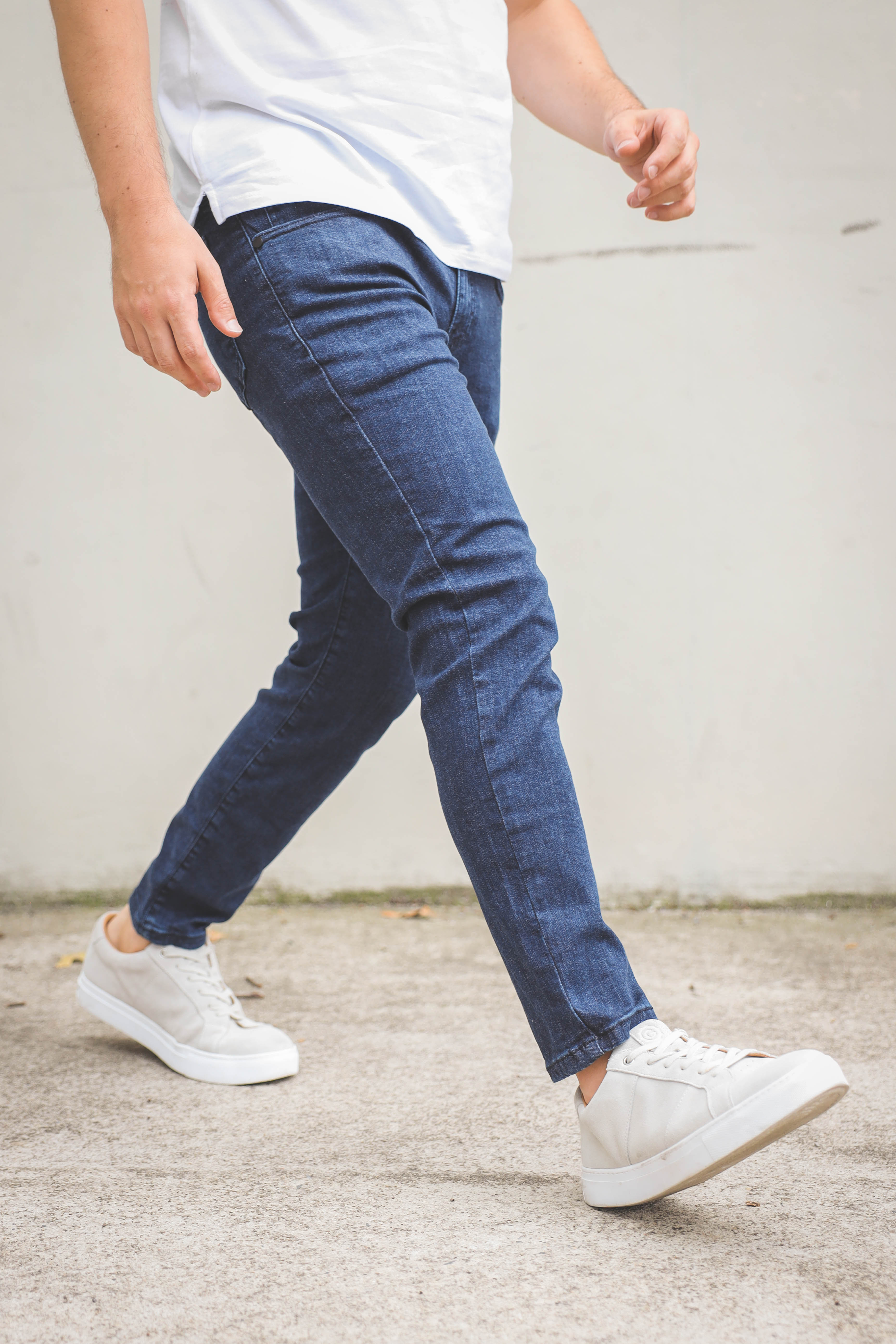 Male walking wearing blue jeans for short men with white canvas shoes